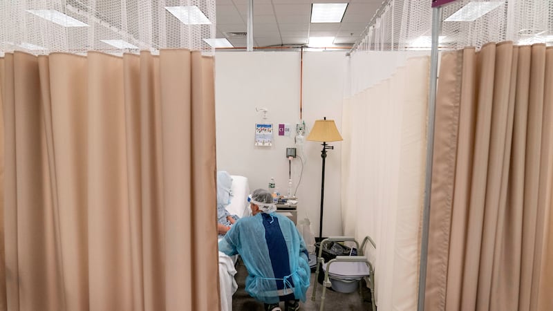 A physical therapist works with a patient at a field hospital operated by Care New England set...